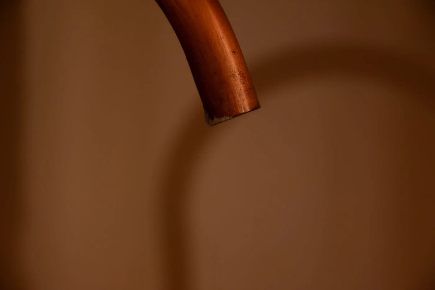 A length of copper pipe casting a shadow on a plain wall